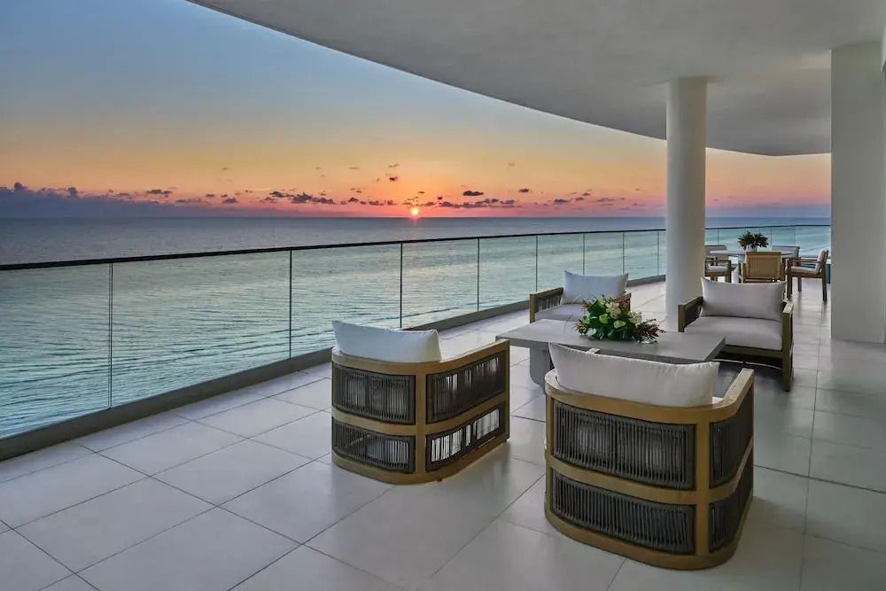 Geräumiger Balkon mit Meerblick bei Sonnenuntergang. Moderne Sitzmöbel.