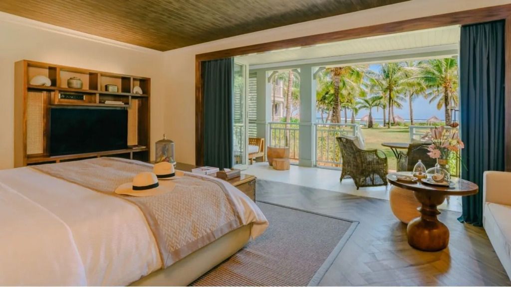 Luxuriöse Junior-Suite mit Doppelbett und Blick auf tropischen Garten und Meer.