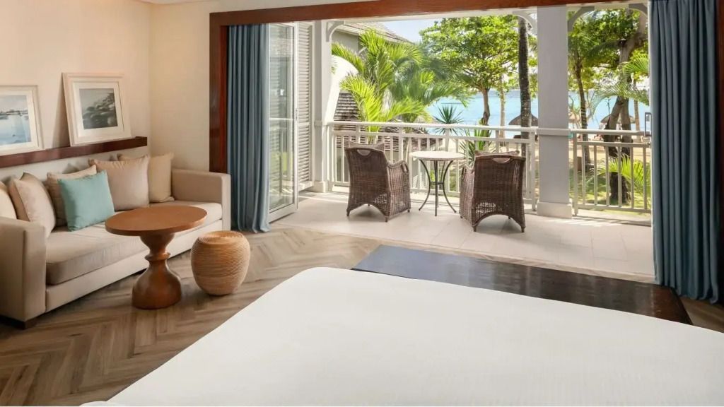 Elegantes Hotelzimmer mit Balkonaussicht auf tropische Gärten und das Meer