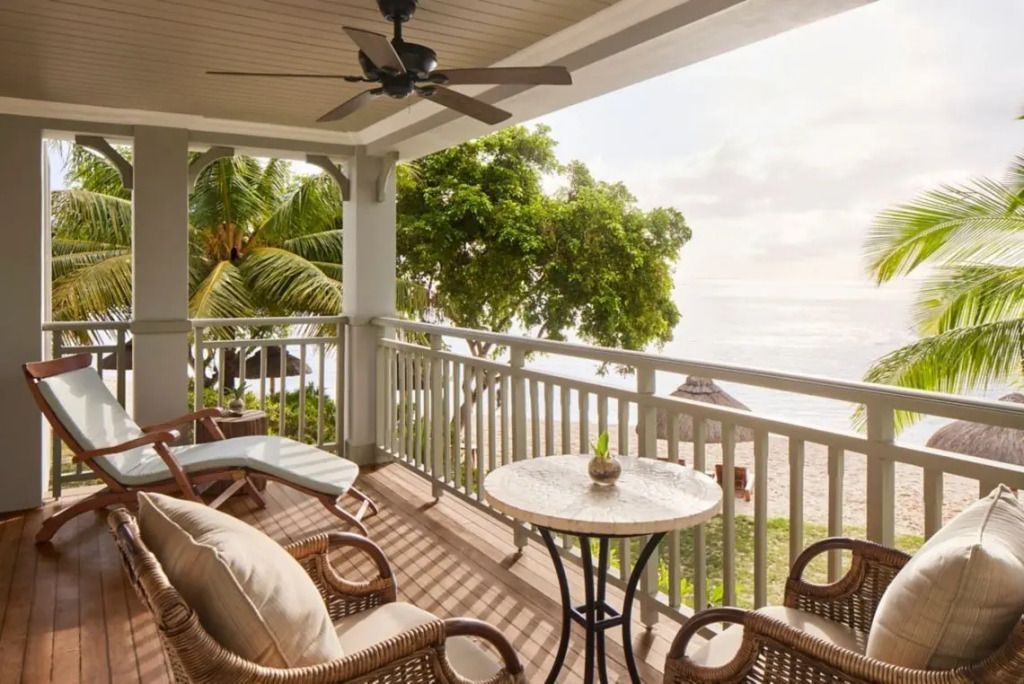 Balkon mit gemütlichen Sitzmöbeln und Blick auf Palmen und Strand