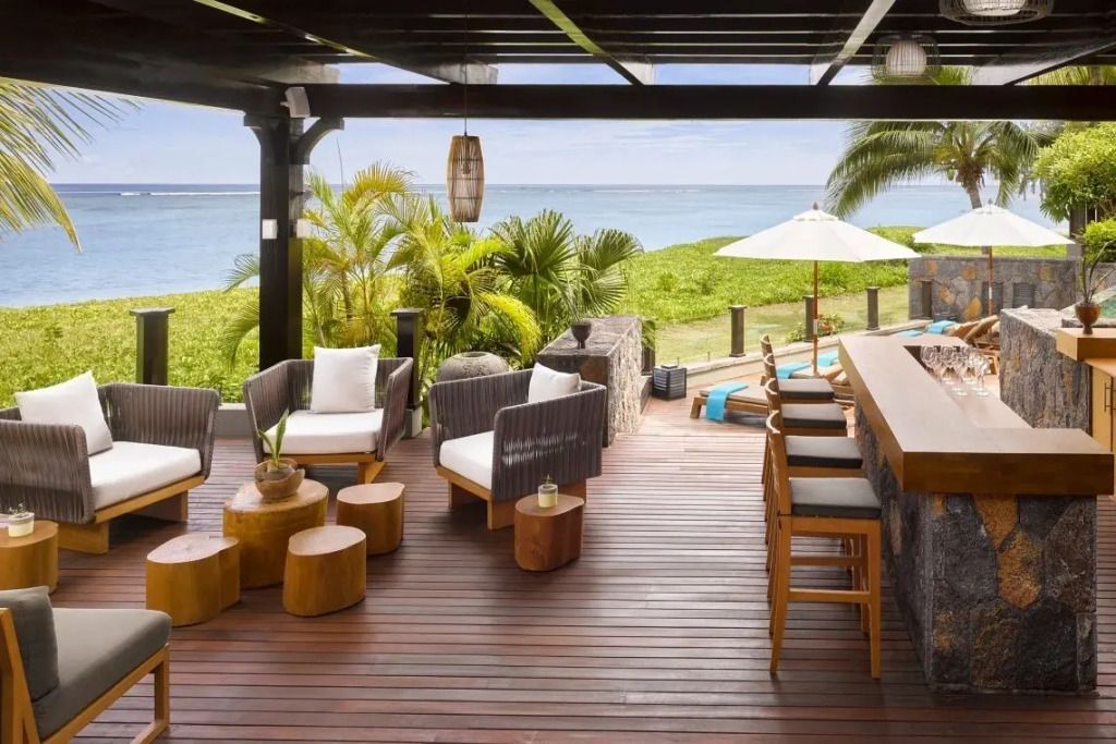 Strand-Lounge-Bereich mit Sitzgelegenheiten und Bar auf einer Holzterrasse.