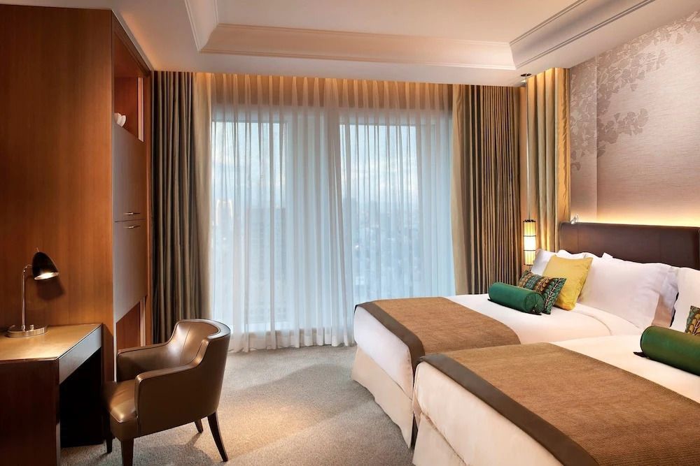 Deluxe Doppelzimmer mit zwei Einzelbetten und großen Fenstern mit Stadtblick