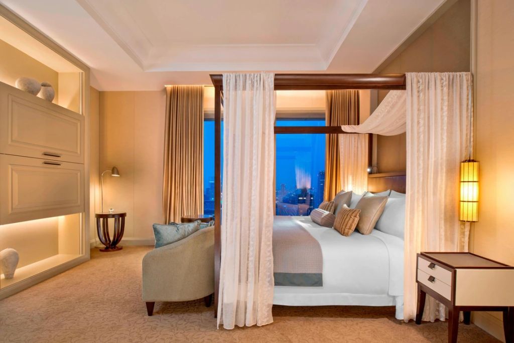 Elegantes Schlafzimmer mit Himmelbett und Skyline-Blick bei Abenddämmerung