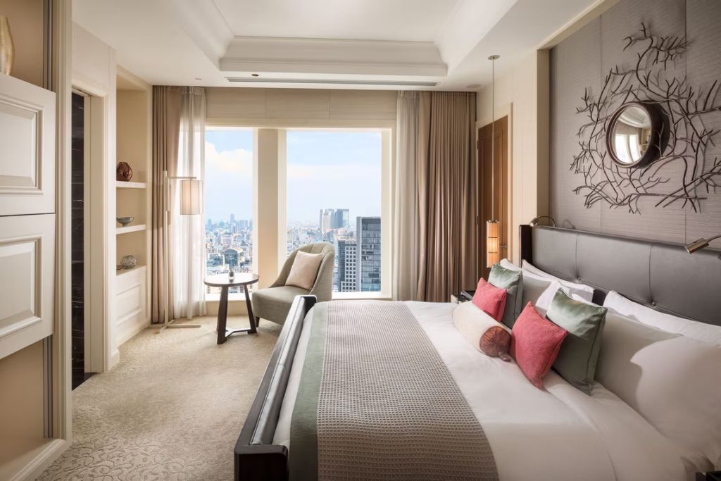 Modernes Zimmer mit Doppelbett und Skyline-Aussicht durch große Fenster