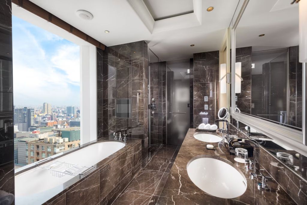 Luxuriöses Badezimmer mit dunklem Marmor und Fenstern mit Stadtblick