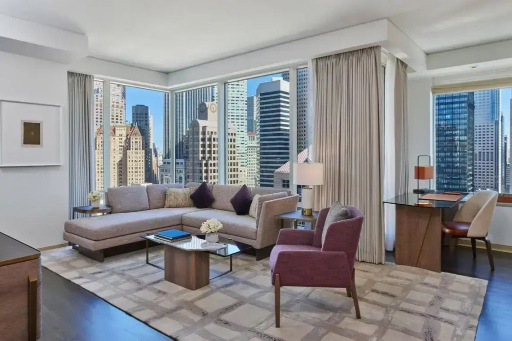 Elegantes Wohnzimmer mit großen Fenstern und Stadtblick von der Astor Doppel Suite