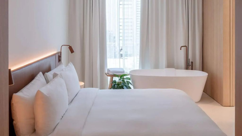 Elegantes Schlafzimmer mit freistehender Badewanne und großen Fenstern