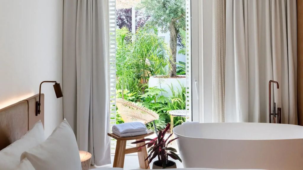 Helligkeit im Schlafzimmer mit Badewanne und Ausblick auf tropischen Garten