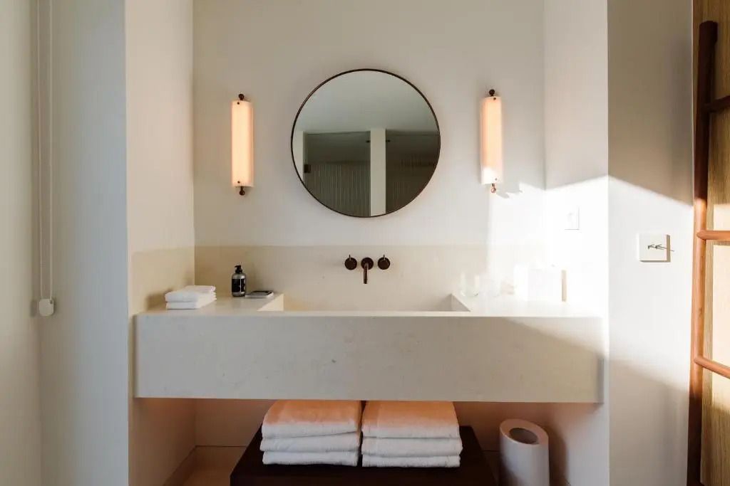 Minimalistisches Badezimmer mit rundem Spiegel und modernen Armaturen