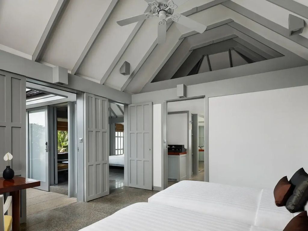 Helles Schlafzimmer mit hoher Decke und mehreren Betten.
