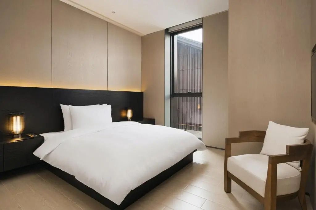 Helles Hotelzimmer mit großem Bett und minimalistischer Einrichtung.