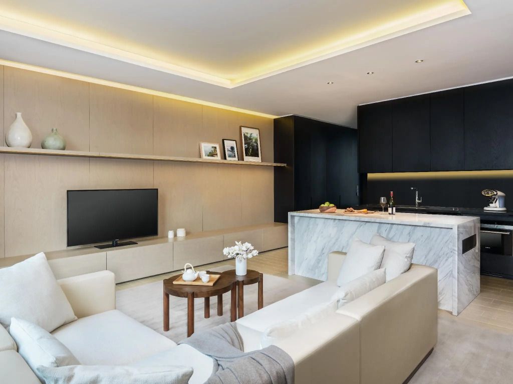 Elegantes Wohnzimmer in neutralen Tönen mit Fernsehbereich und Küchenzeile
