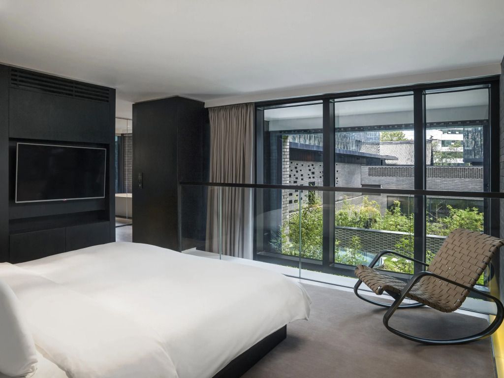 Helles Schlafzimmer mit Blick auf Gartenbereich durch große Fenster