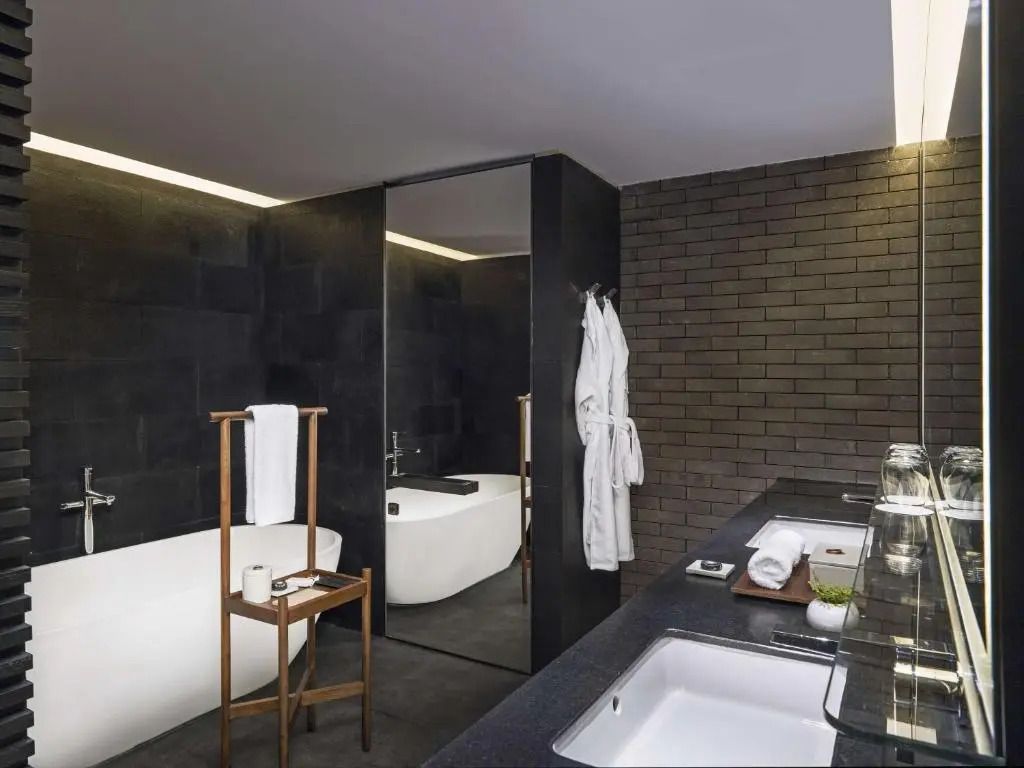 Moderne Suite-Badewanne mit dunklen Wänden und Doppelwaschbecken