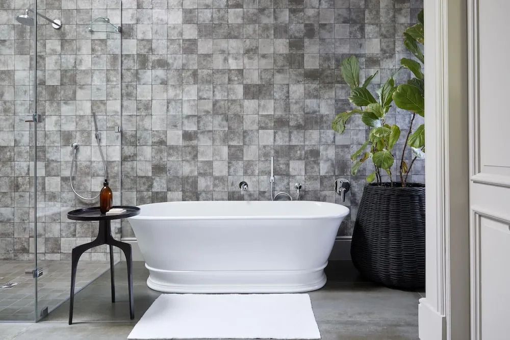 Moderne Badewanne mit dekorativer Wandgestaltung und grüner Pflanze