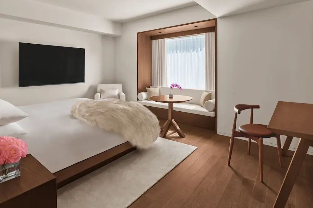 Elegantes Hotelzimmer mit Doppelbett, TV und gemütlicher Sitzecke mit Blick auf die Stadt