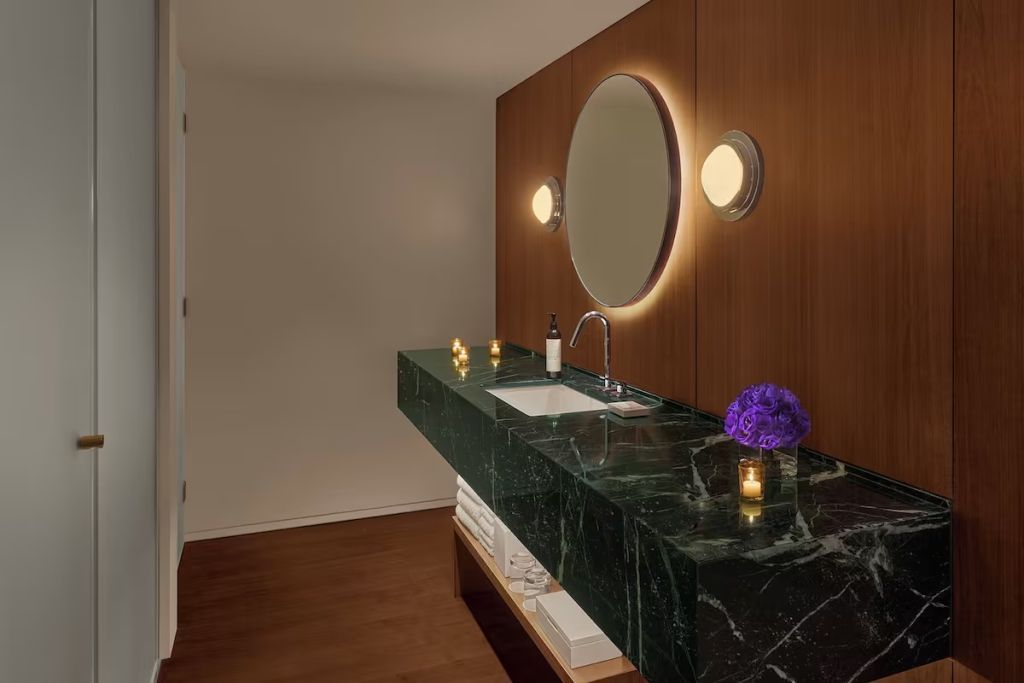 Modernes Badezimmer mit grünem Marmortisch und weicher Beleuchtung.