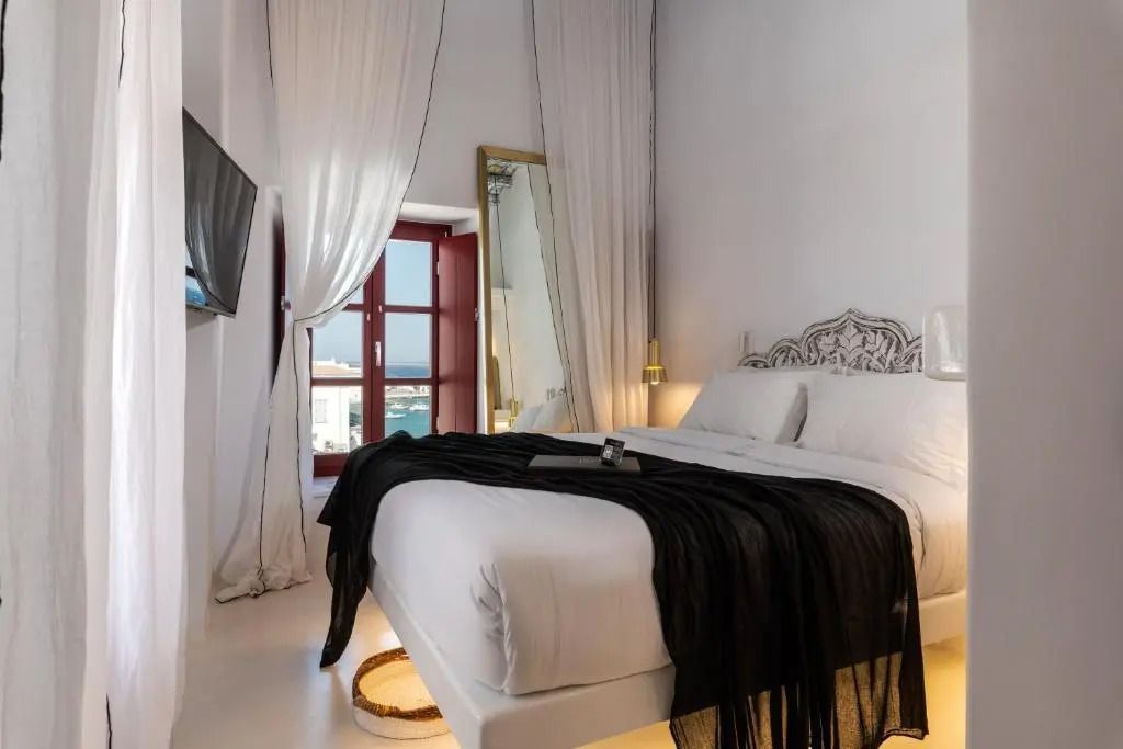 Helles Schlafzimmer mit Meerblick und luxuriösen Stoffen im Deluxe Zimmer.