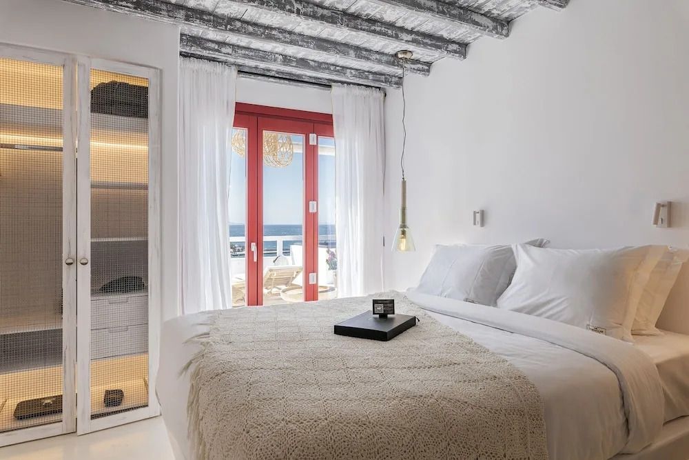 Helles Schlafzimmer mit Doppelbett und Meerblick durch große Fenster