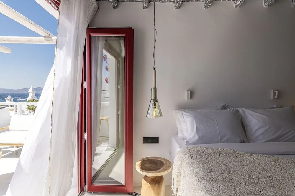 Schlafzimmer mit offenem Fenster und Blick auf das Meer und die Terrasse