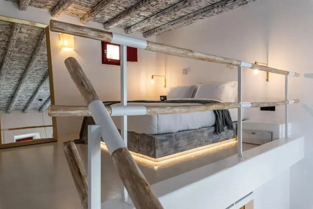 Doppelbett auf einer erhöhten Plattform mit rustikalen Holzbalken