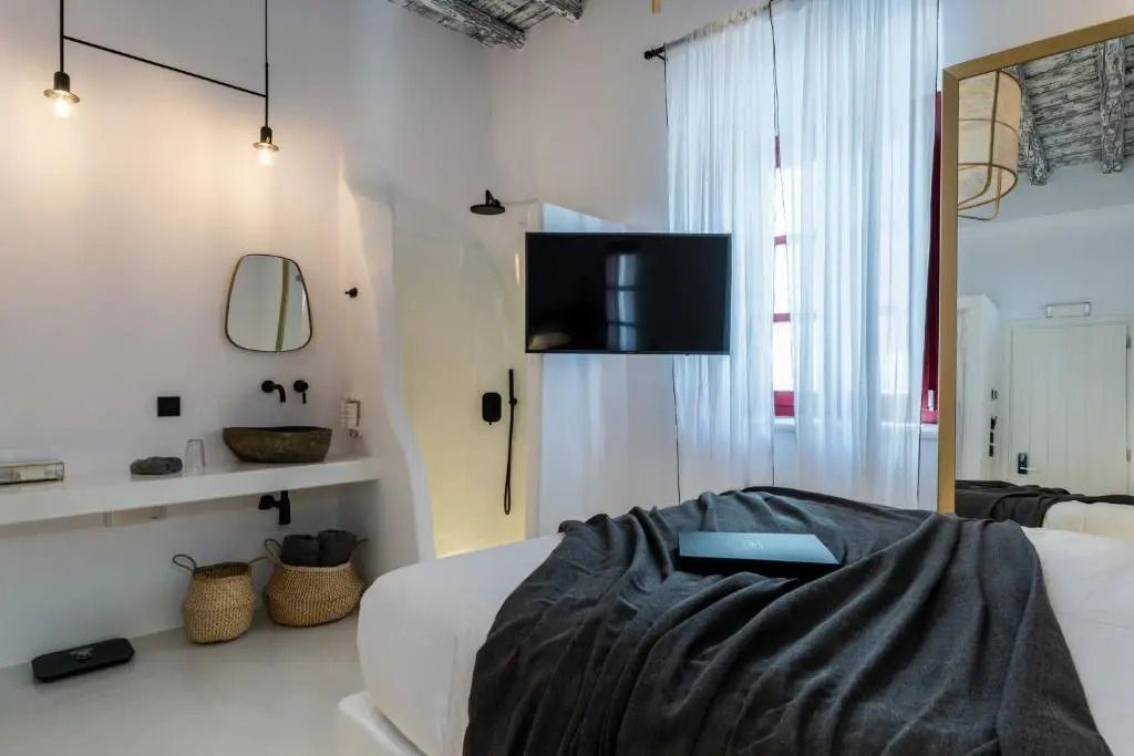 Zimmer mit schwarzem TV an der Wand, modernen Möbeln und weißen Vorhängen