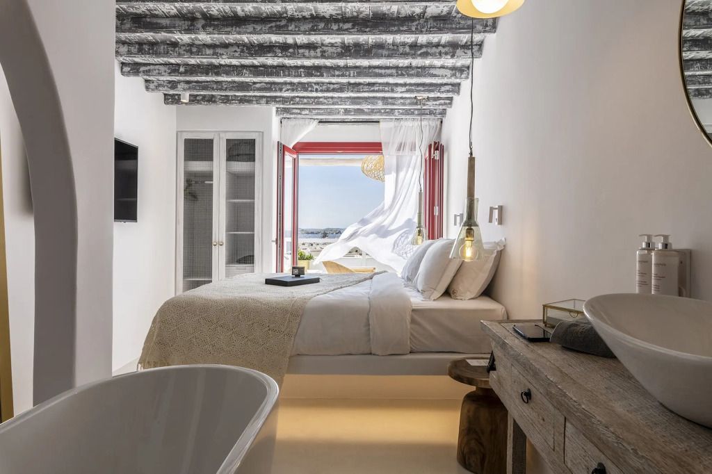 Helles Schlafzimmer mit freiliegenden Holzbalken, Balkon und Blick auf das Meer