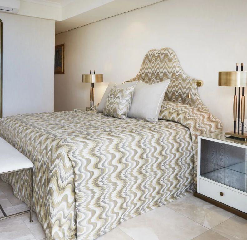 Elegantes Zimmer mit Doppelbett, gemusterten Kissen und goldenen Akzenten