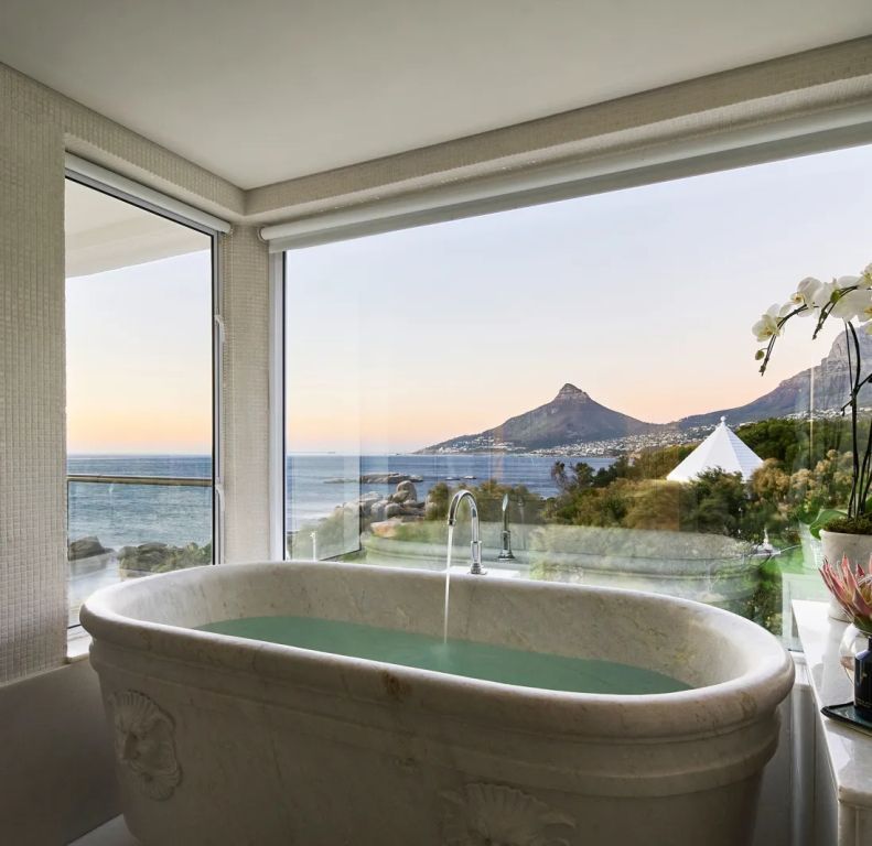 Freistehende Badewanne mit spektakulärem Blick auf das Meer und die Berge.
