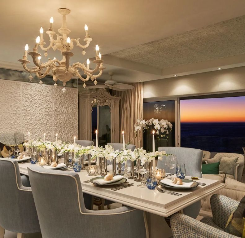 Elegantes Esszimmer mit Kerzenlicht und Blick auf den Sonnenuntergang über dem Ozean