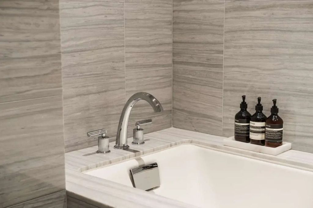 Luxuriöse Badewanne mit stilvollen Armaturen und Fliesenverkleidung