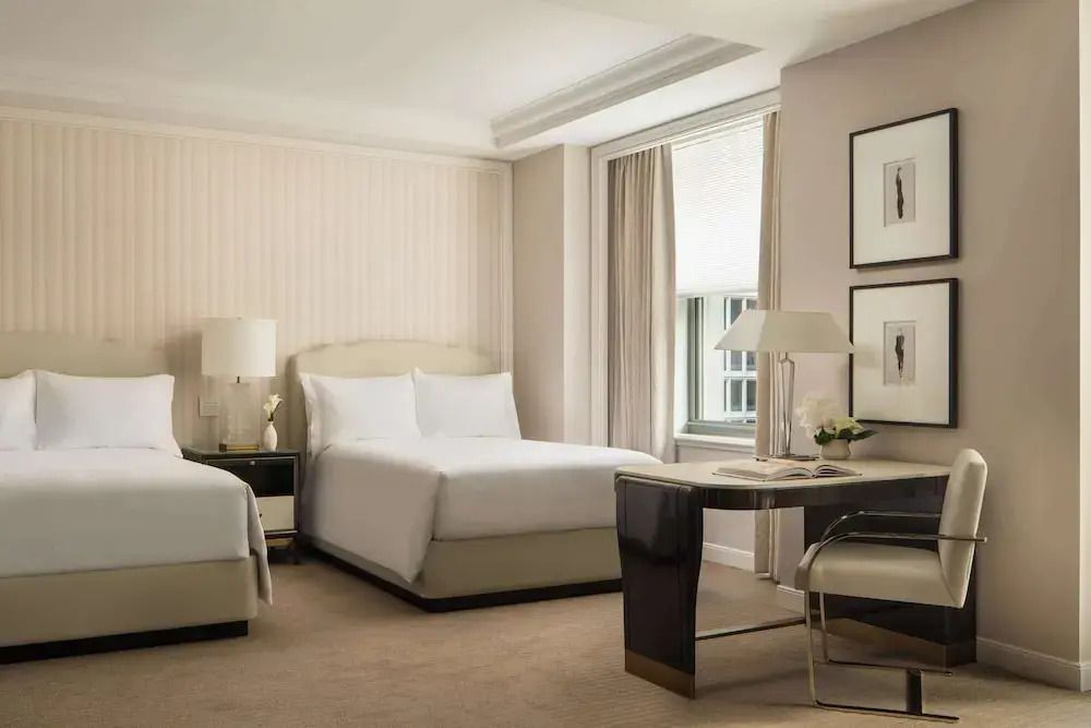 Zwei Einzelbetten in einem edel eingerichteten Hotelzimmer mit Schreibtisch und Kunstwerken