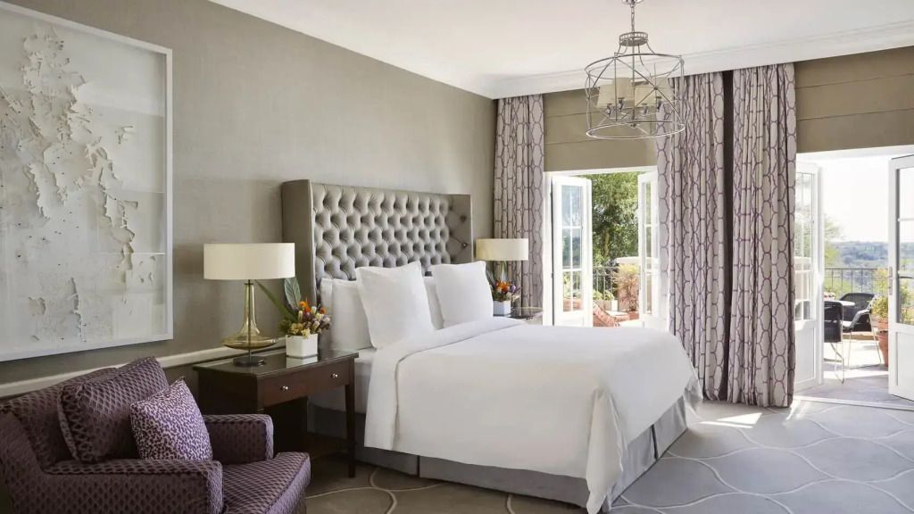 Helles Schlafzimmer mit Doppelbett, eleganter Einrichtung und Balkon mit Aussicht.