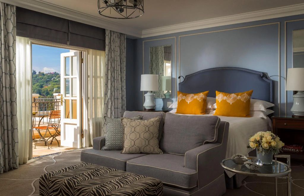 Elegantes Hotelzimmer mit Doppelbett und Gartenblick mit Zugang zum Balkon.