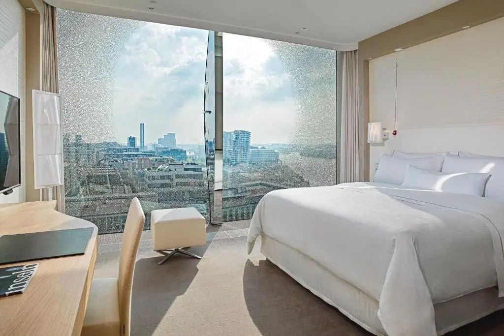 Zimmer mit Doppelbett und Panoramafenster mit teilweisem Wasserblick