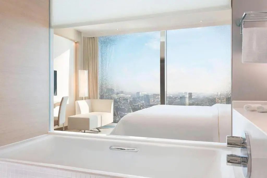 Zimmeransicht mit Badewanne und Blick auf die Stadt durch Panoramafenster