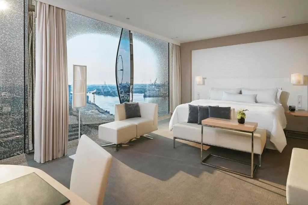 Geräumige Suite mit Sitzbereich und Panoramablick auf den Hafen.
