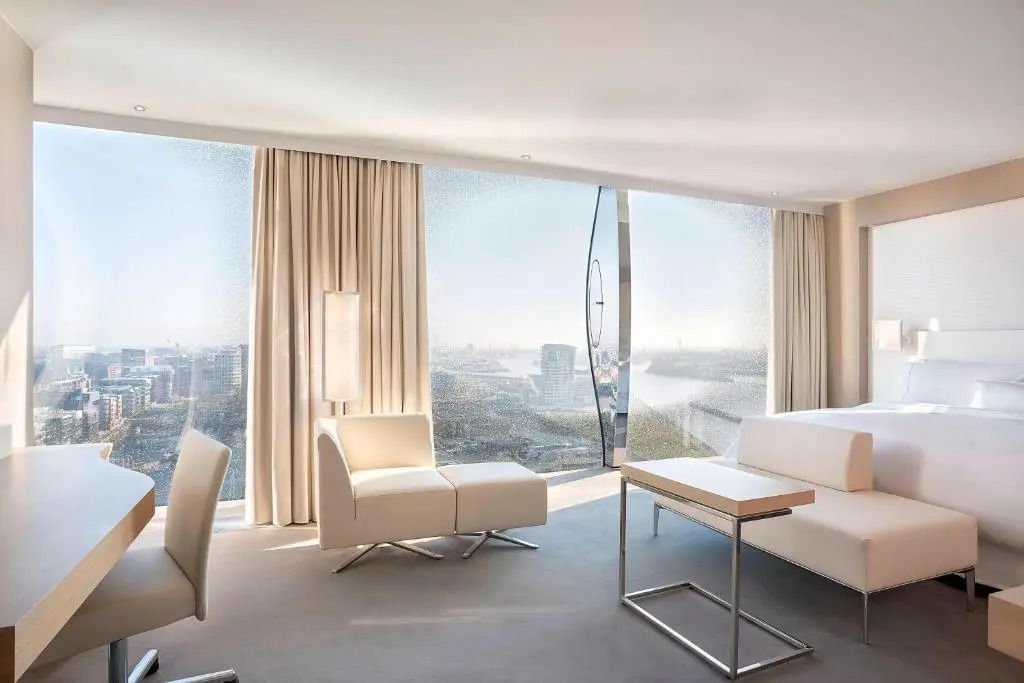 Moderne Suite mit Sitzbereich und großen Fenstern mit Hafenblick.