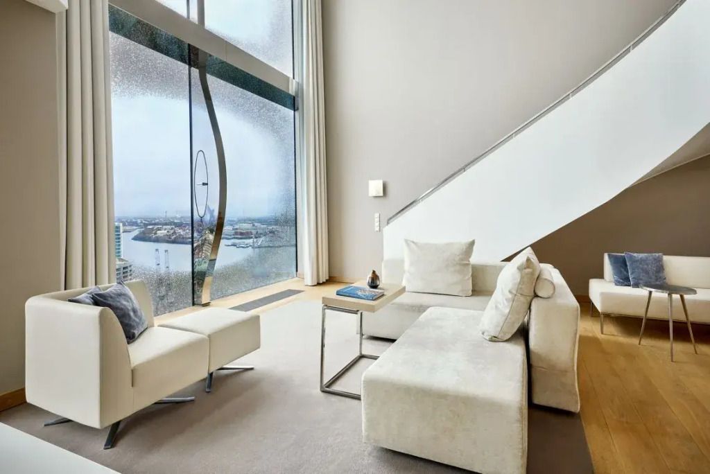 Heller Wohnbereich einer Suite mit großer Fensterfront und Hafenblick im Westin Hamburg.