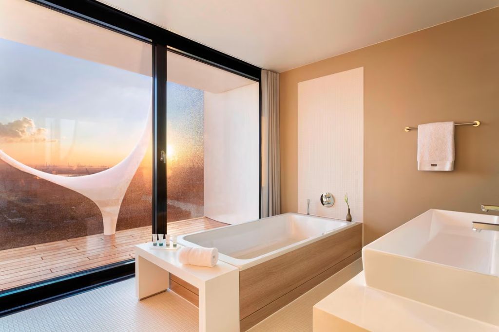 Badezimmer mit freistehender Badewanne und Balkon mit Sonnenuntergang