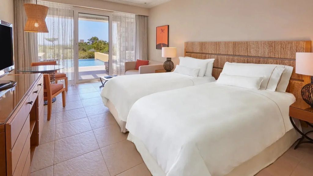 Modernes Hotelzimmer mit zwei Einzelbetten und Balkon mit Gartenaussicht