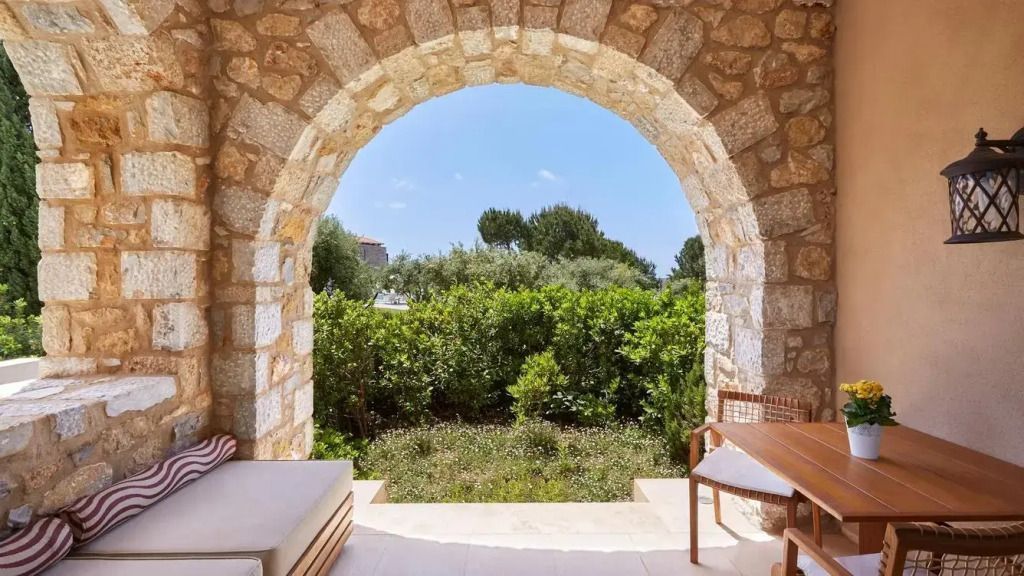 Steinbogen überblickt grünen Garten, bietet mediterrane Atmosphäre.