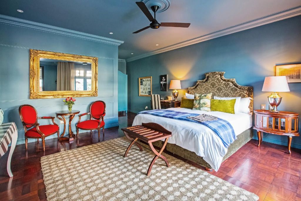 Elegantes Schlafzimmer mit großem Bett, goldener Spiegel und Sessel im Park Hyatt Johannesburg
