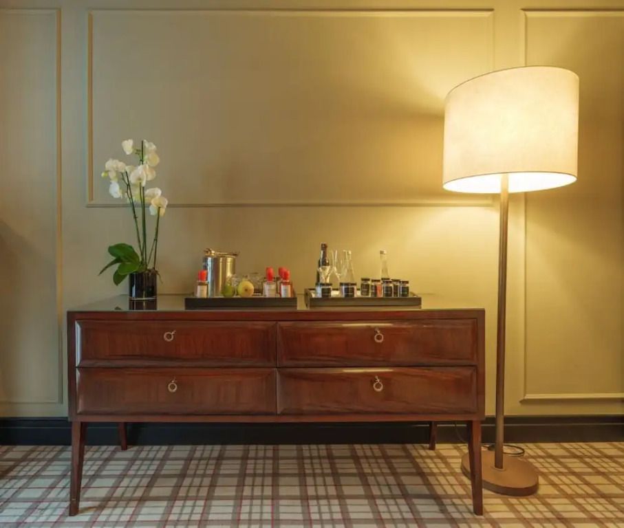 Elegantes Sideboard mit Orchidee und Stehlampe im Hotelzimmer