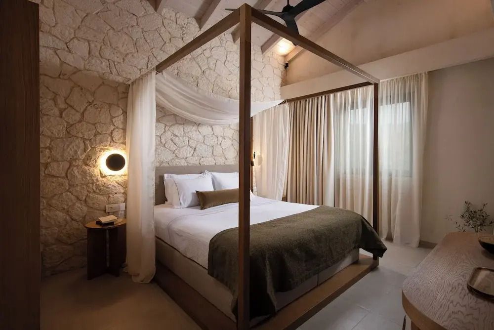 Helles Schlafzimmer der Junior-Suite mit Himmelbett und Steinwandakzent.
