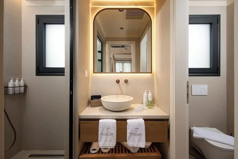 Modernes Badezimmer mit beleuchtetem Spiegel und Steinwaschbecken.
