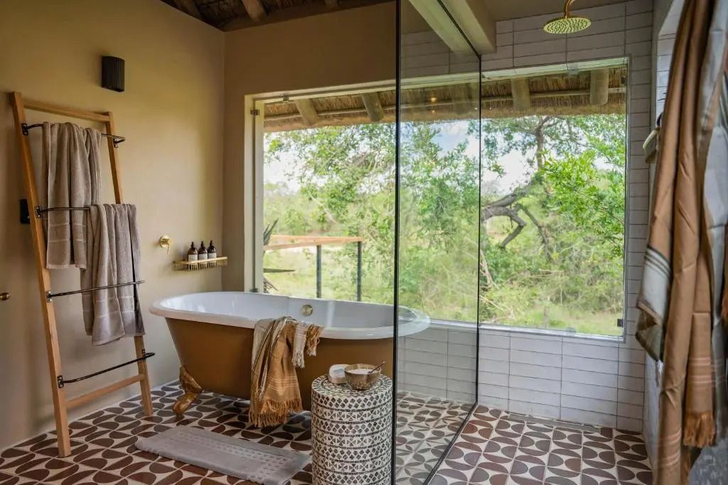 Luxuriöses Badezimmer mit freistehender Badewanne und Panoramablick auf die Natur