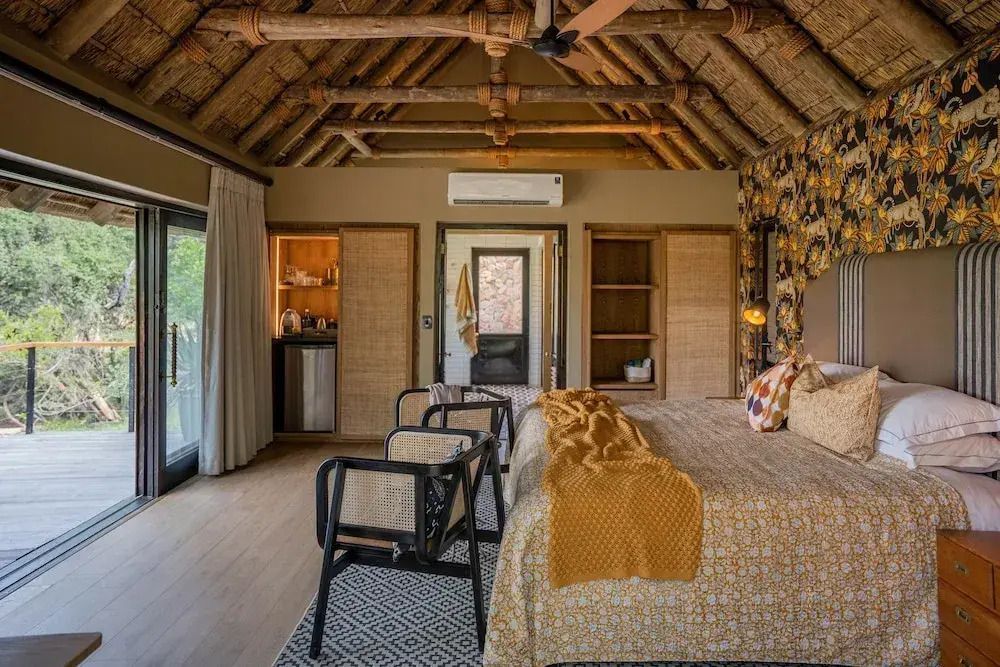 Luxuriöse Suite mit Holzbalkendecke, Bett und Blick auf den Balkon.