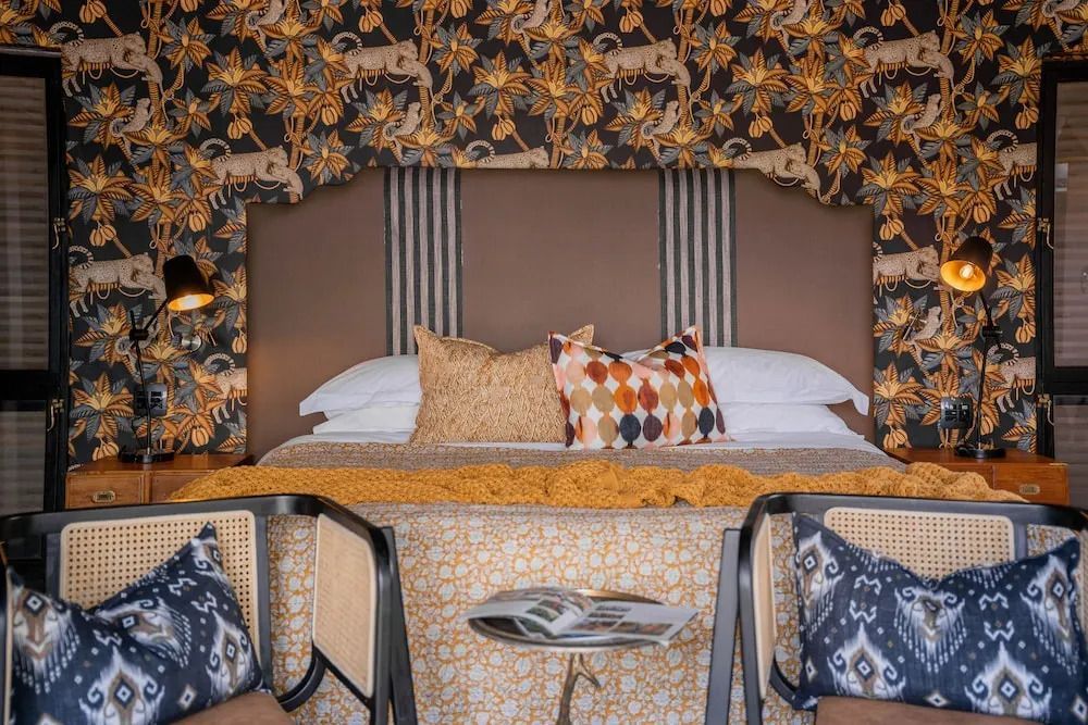 Elegantes Bett mit kunstvoller Tapete und dekorativen Kissen.