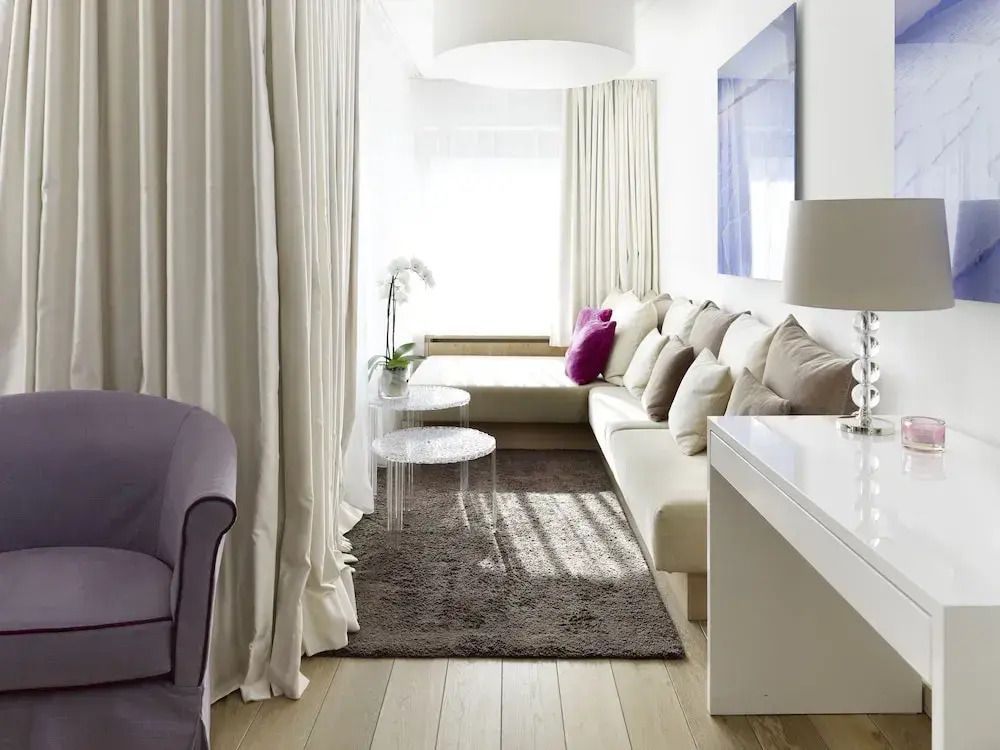 Elegantes Wohnzimmer in der Deluxe Suite mit hellen Vorhängen und moderner Einrichtung